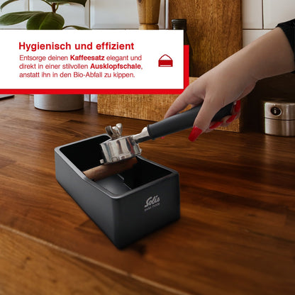 Barista entsorgt Kaffeereste hygienisch und effizient in der Solis Ausklopfschale.