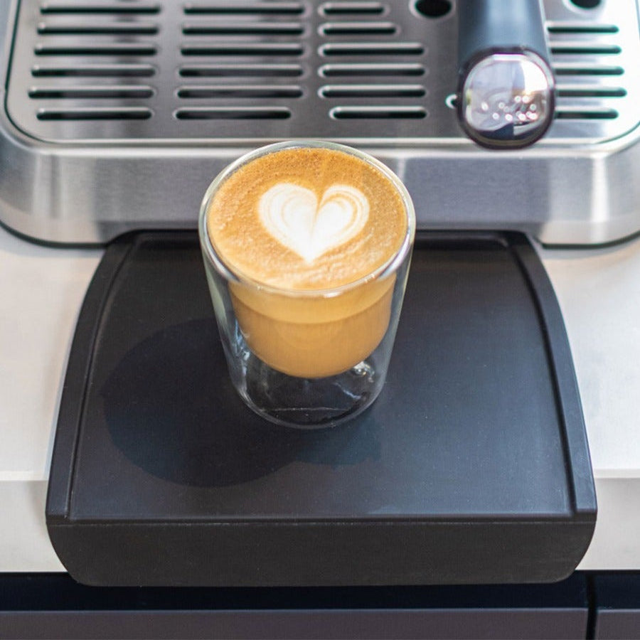 Cappuccino-Tasse auf der Solis Tampingmatte vor Espressomaschine